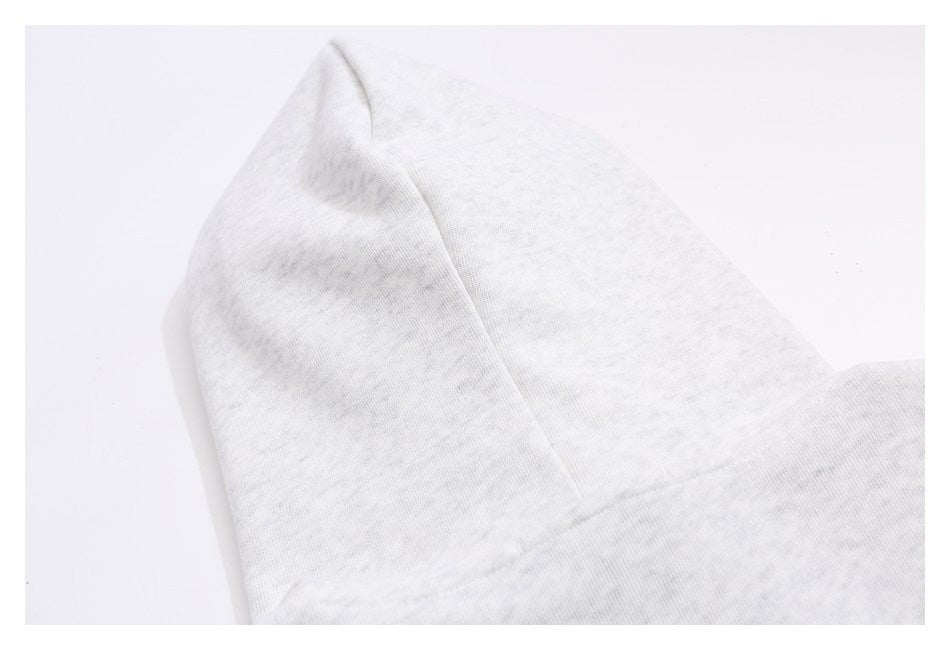 Close-up of light gray heather knit fabric with a curved stitched seam and folded edge.