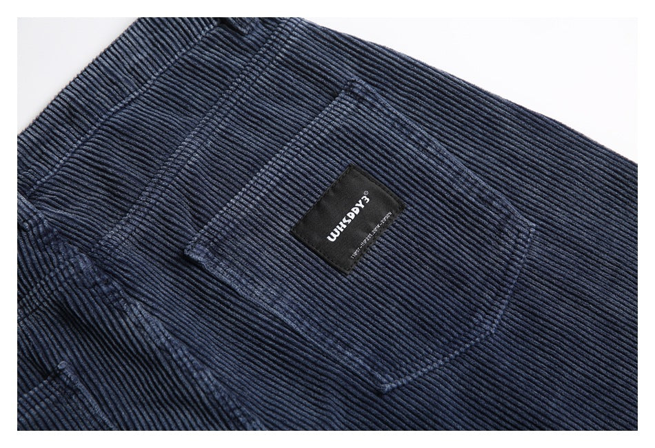 Close-up of a black sewn label on a navy ribbed corduroy back pocket.