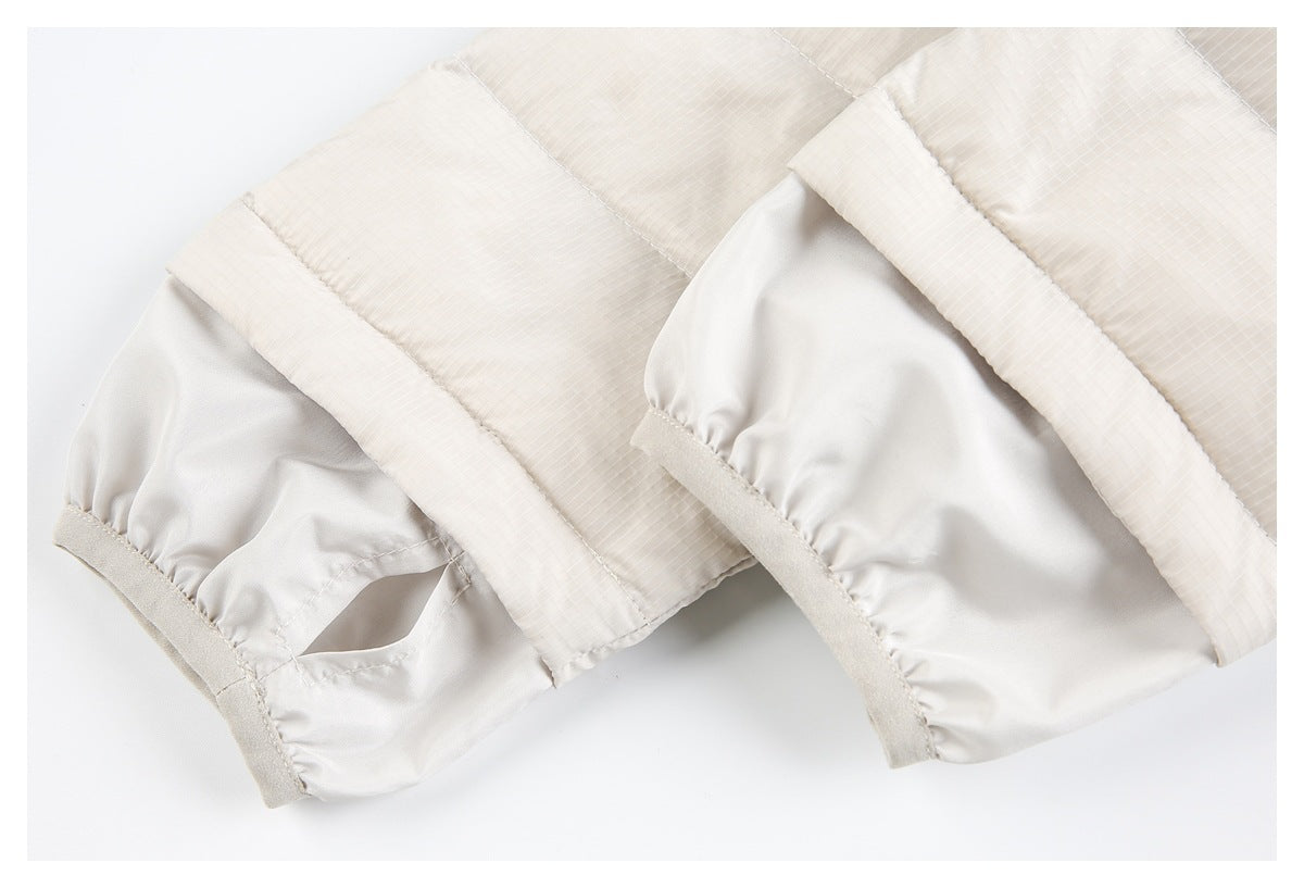 Close-up of an ivory jacket sleeve cuff with gathered stitching and a pale grid-patterned panel.