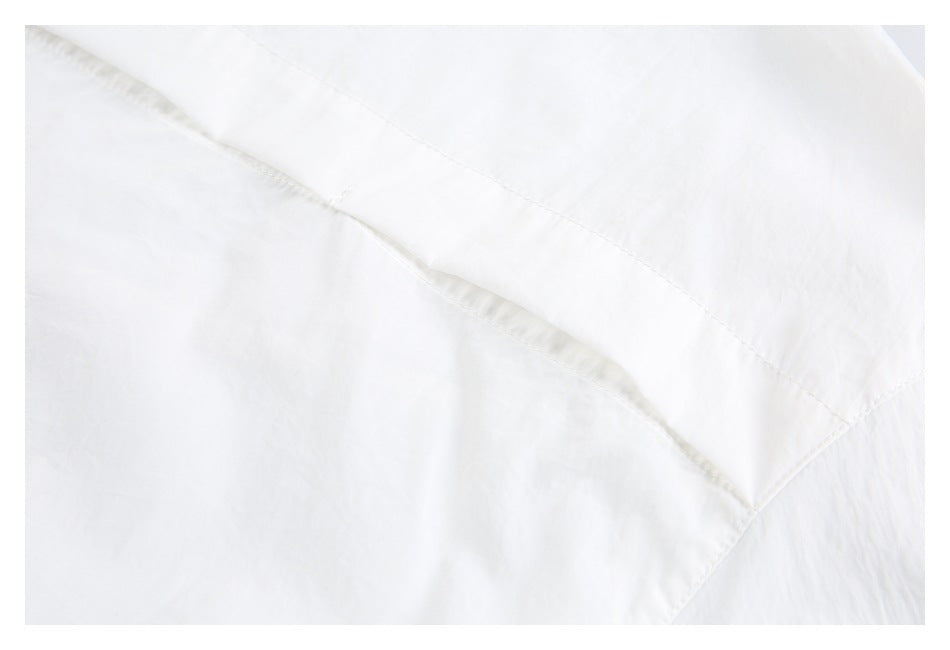 Close-up of white fabric with diagonal stitched seams.