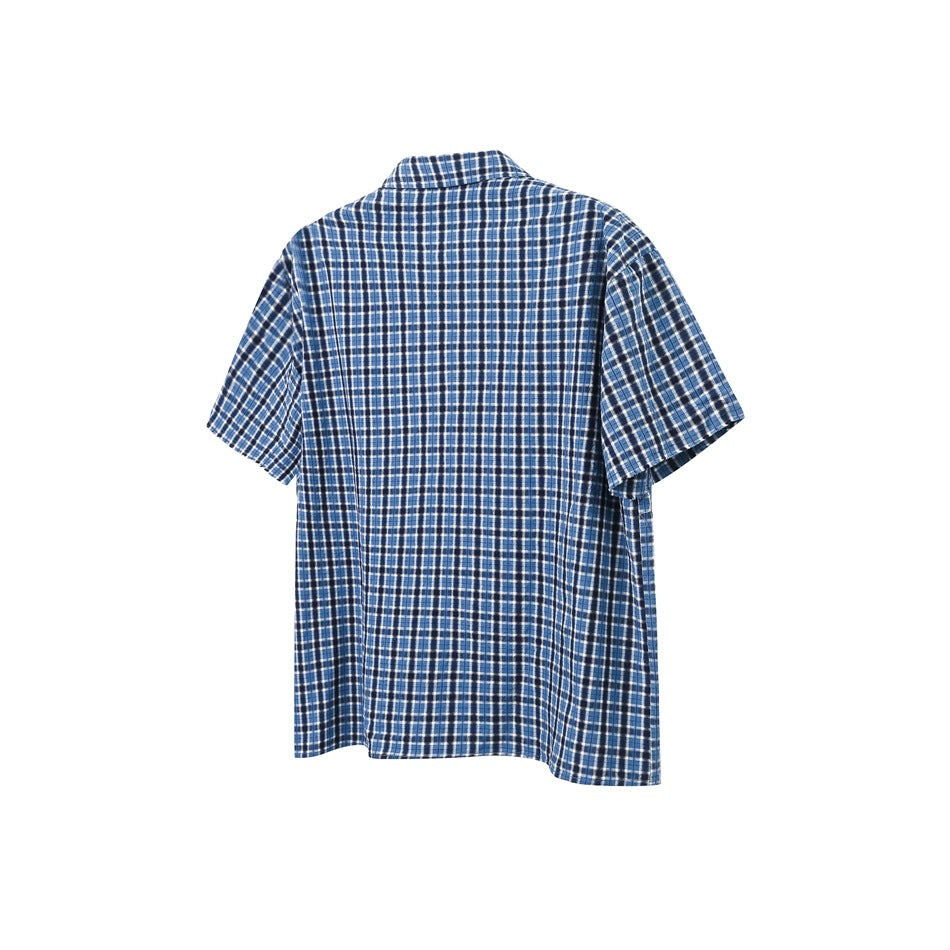 Back view of a blue, black, and white plaid short-sleeve button-up shirt on a white background.