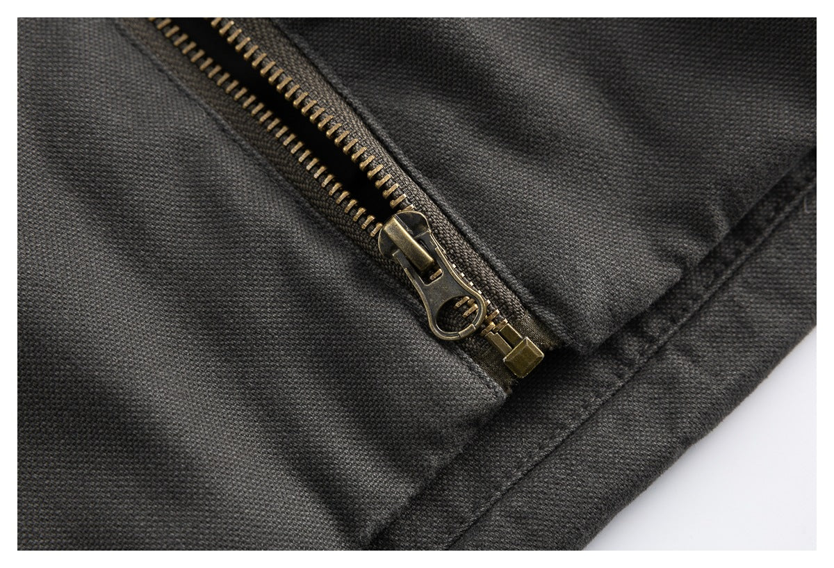 Close-up of an antique-brass zipper and stitching on dark jacket fabric.