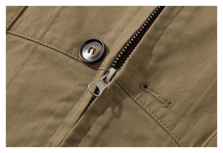 Close-up of the tan garment's front zipper, dark button, stitching and small buttonhole.