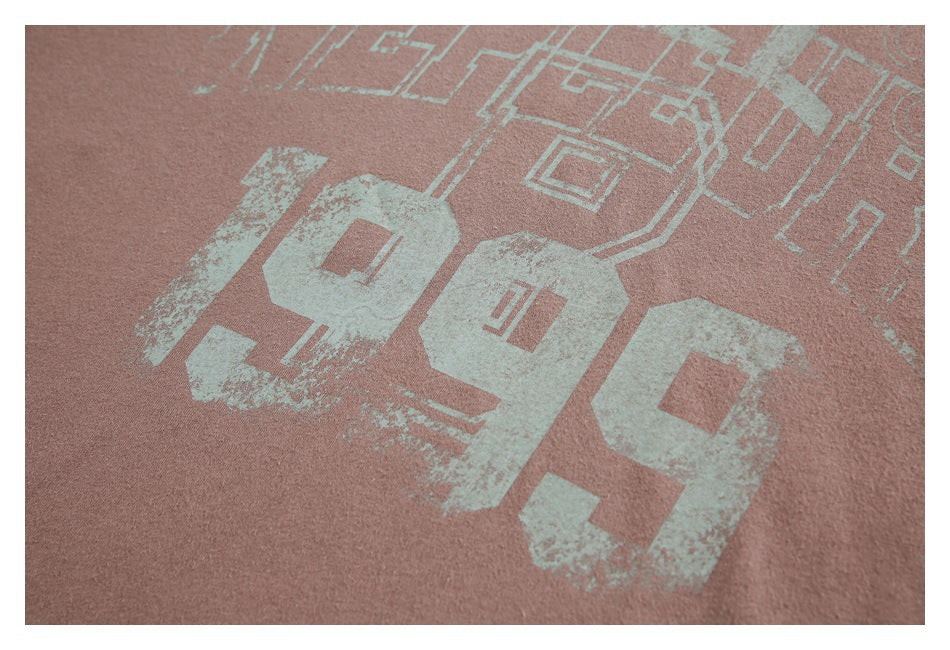 Close-up of dusty rose fabric with a distressed pale mint numeral graphic and geometric outlines.