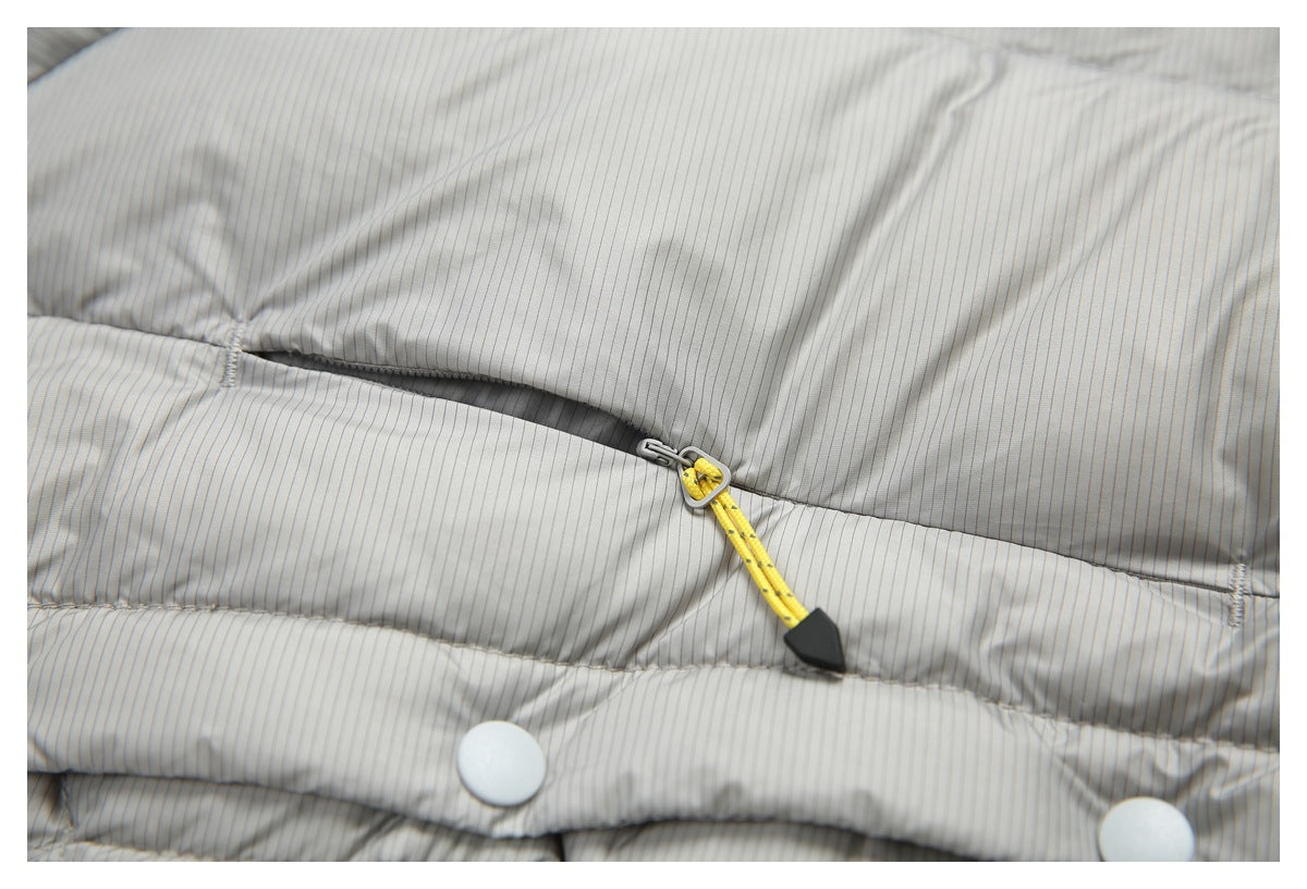 Close-up of a zipper with a yellow pull cord and snap fasteners on the striped lining of a light gray jacket.