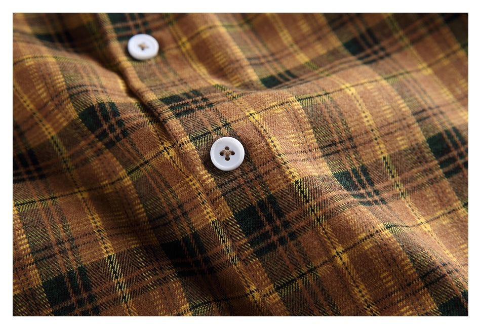 Macro view of the shirt’s brown and green plaid fabric and a white four-hole button.