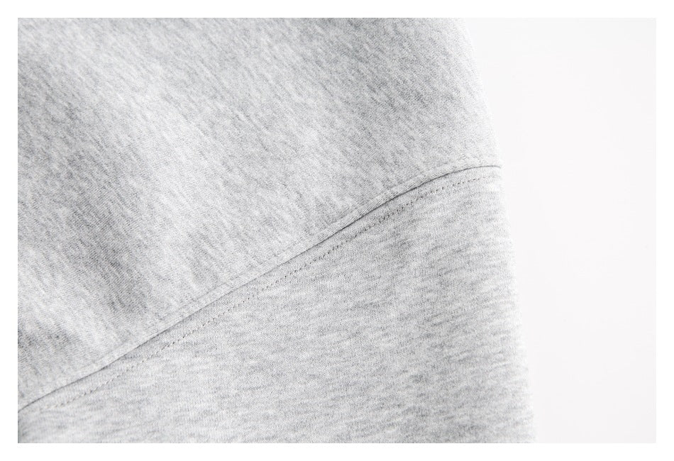 Close-up of light gray heathered fabric with a curved stitched seam.