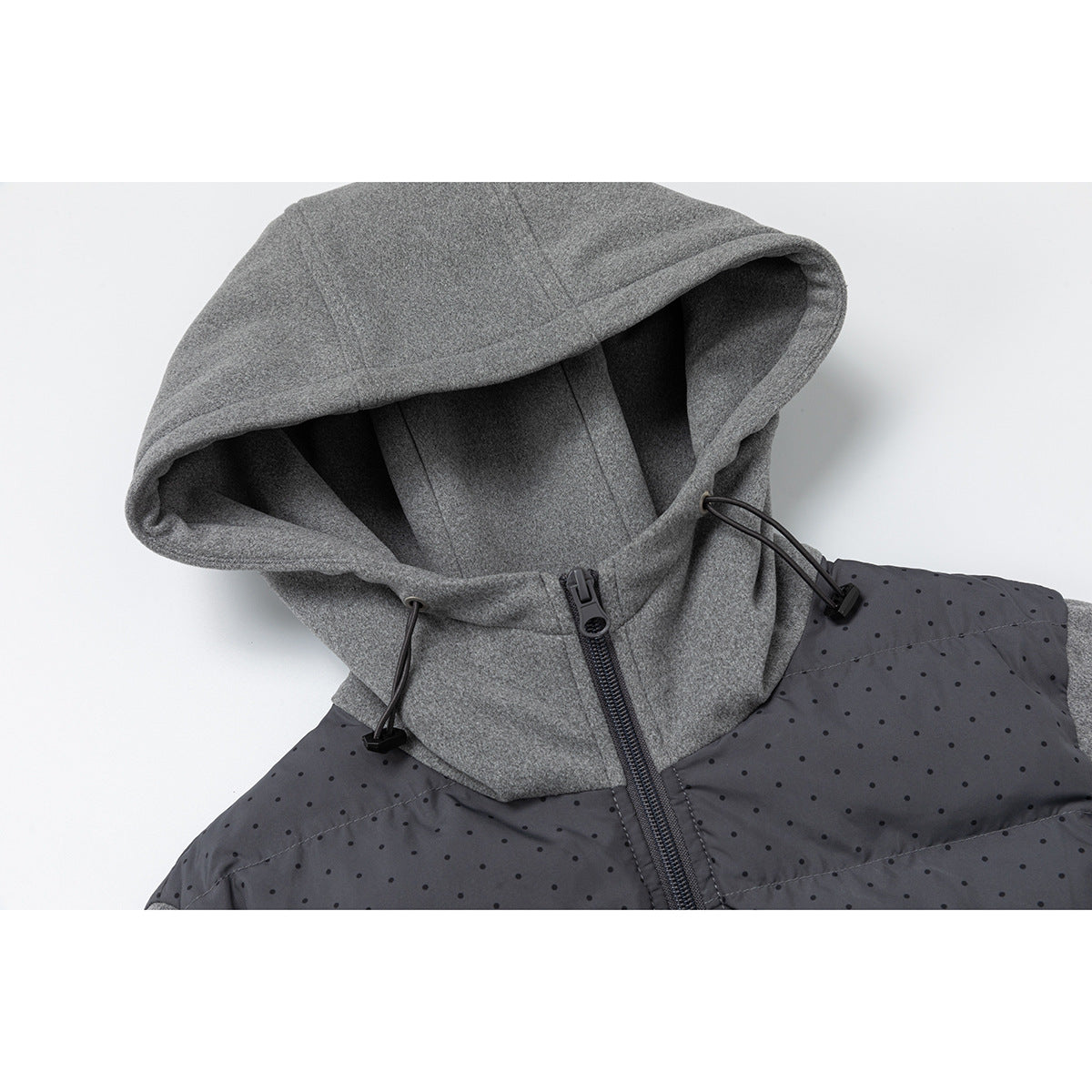 Close-up of a gray hood with black drawcords and zipper above a charcoal dotted jacket panel.
