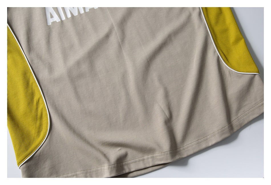 Close-up of the beige shirt hem and yellow side panels edged with white piping.