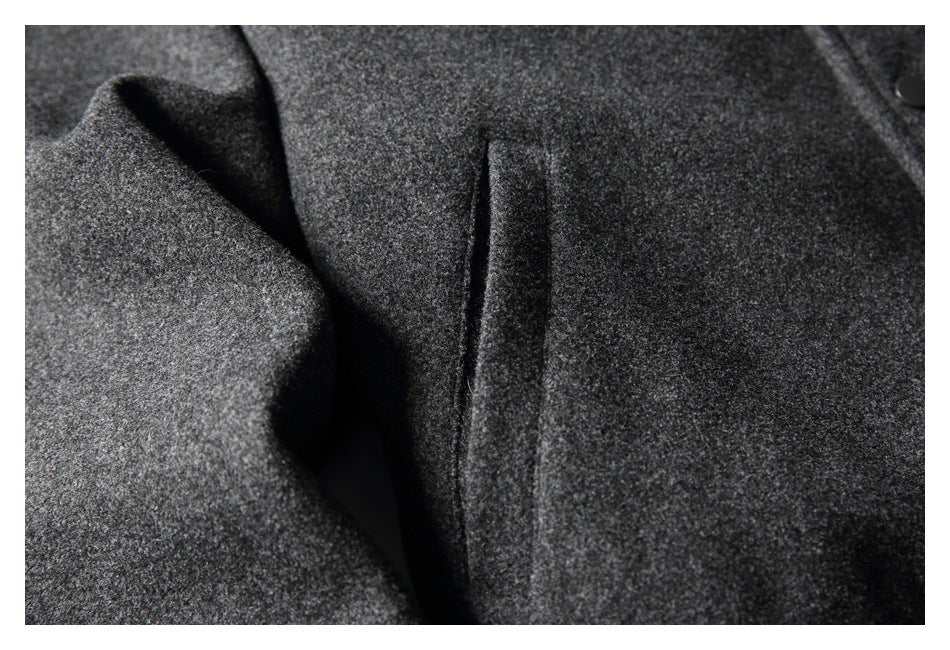 Close-up of a vertical welt pocket on the textured charcoal jacket, with part of a black snap button visible.