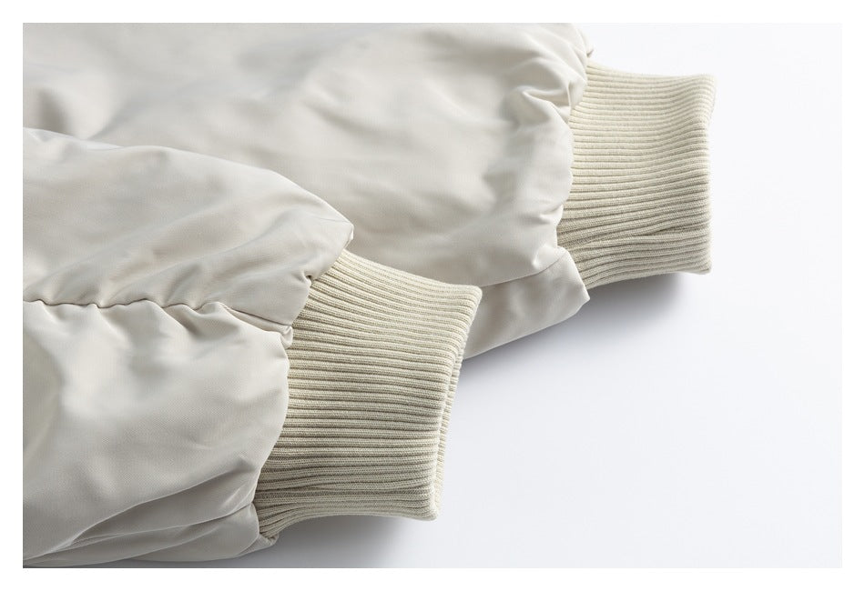 Close-up of two ivory coat sleeves with wide ribbed knit cuffs.
