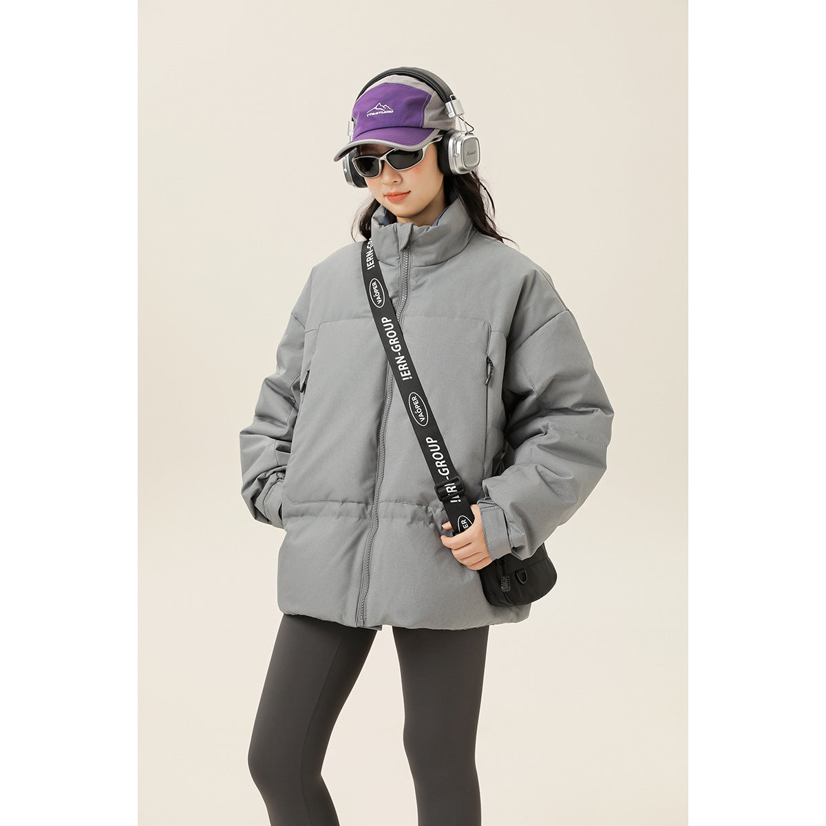 Closer view of a model wearing a gray padded jacket with a high collar, front zipper, and zip pockets.