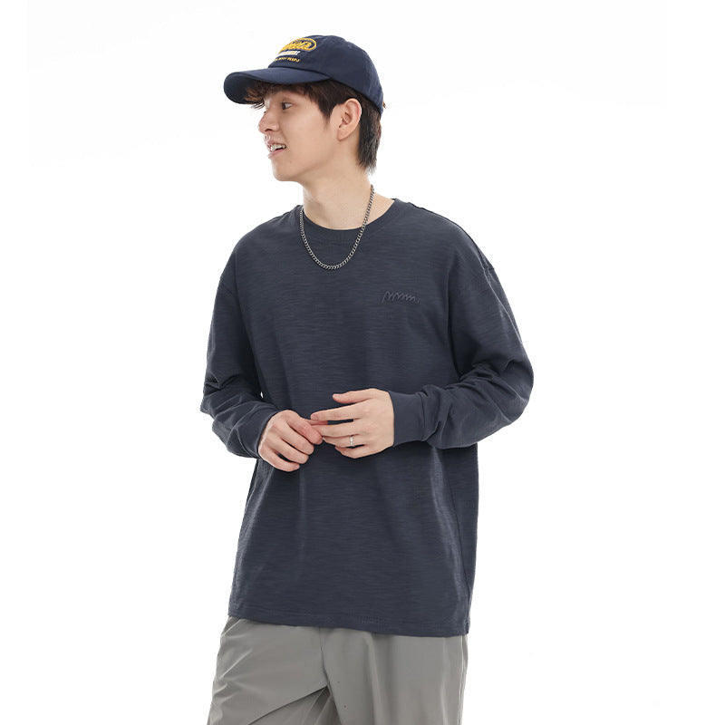 Model wearing a navy long-sleeve crewneck shirt and dark cap against a white background.