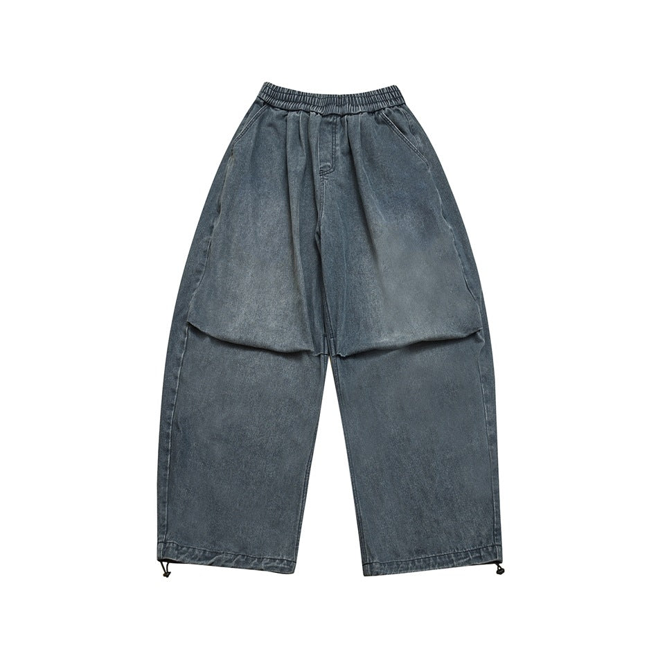 Front view of faded blue wide-leg denim pants with elastic waist, side pockets and hem drawcord toggles
