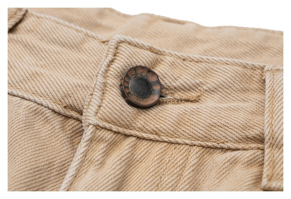 Close-up of a dark metal button on the waistband of beige pants.