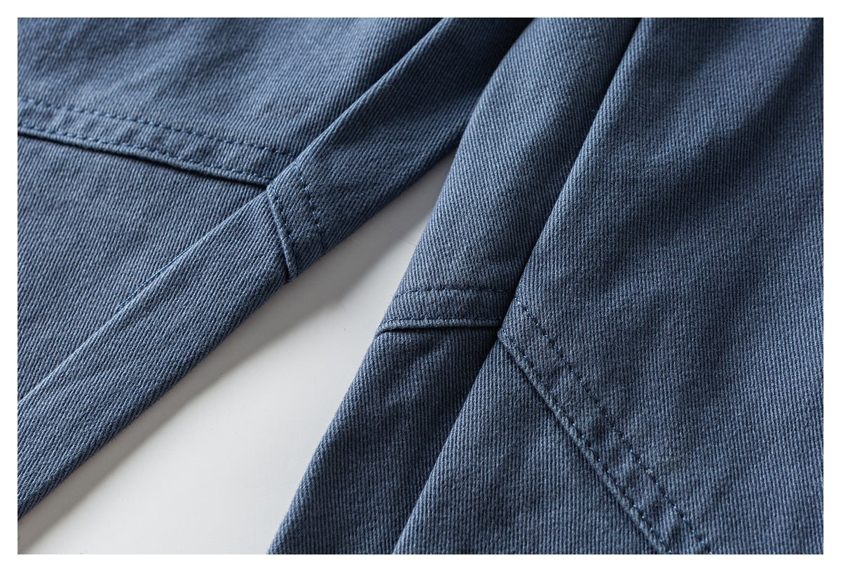 Close-up of blue pants showing stitched seams and folded fabric panels.