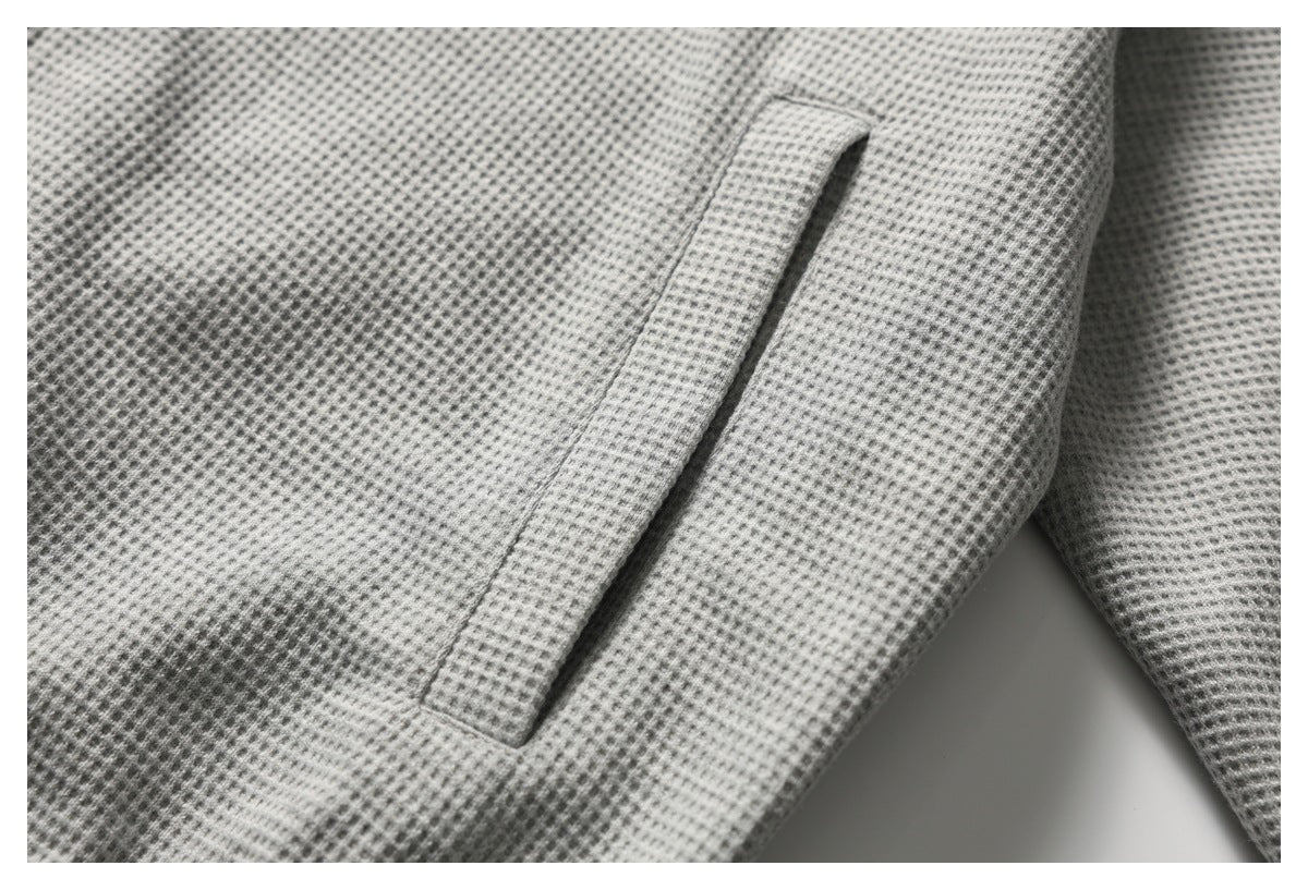 Close-up of a slanted welt pocket on the light gray textured top.
