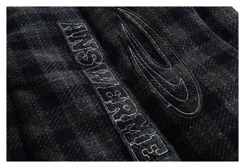 Close-up of outlined Nike Air embroidery on dark charcoal fabric with blue flecks.