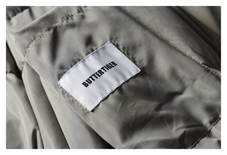 Close-up of a sewn-in white Butterfly label on taupe garment fabric.