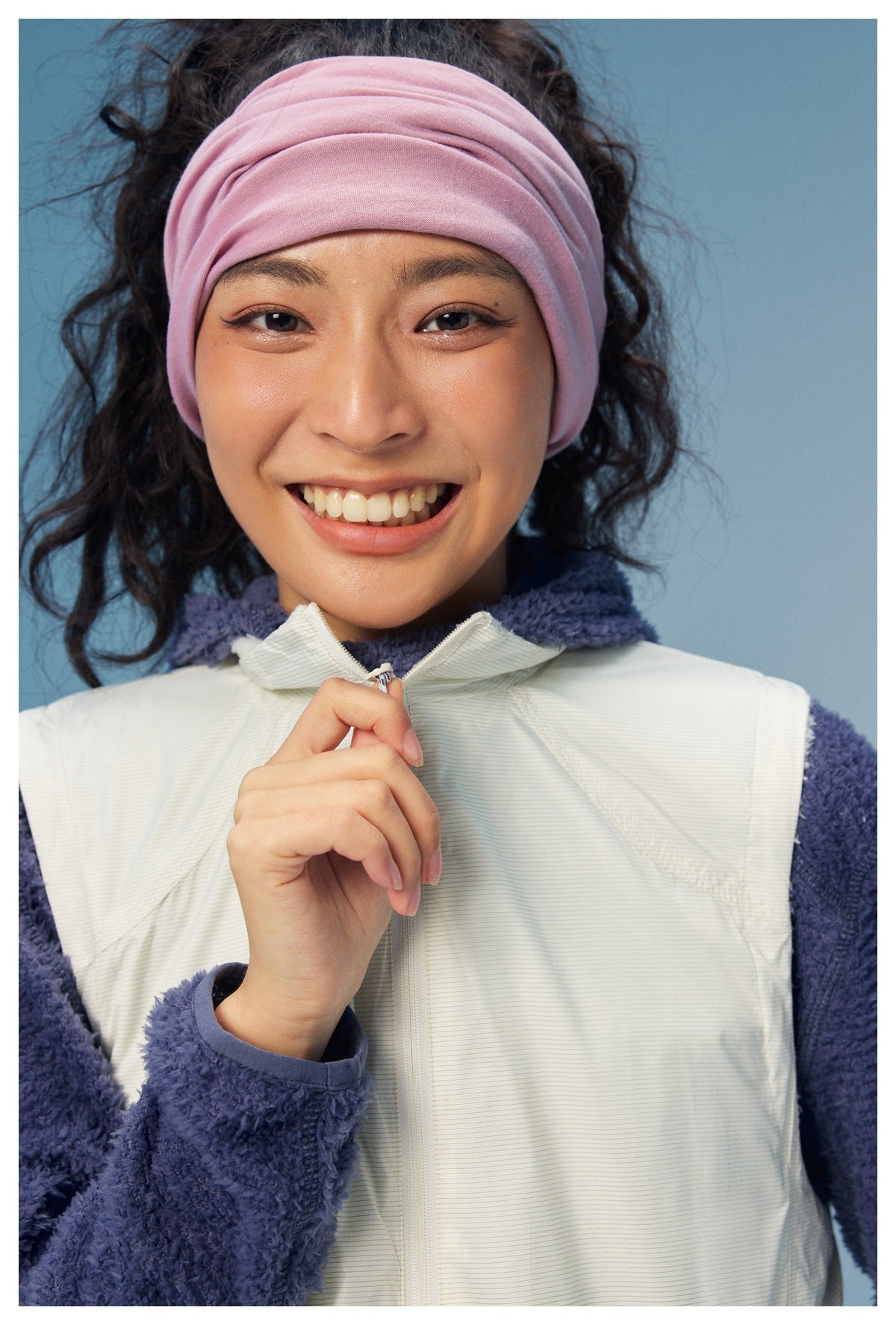 Close-up of an off-white zip vest layered over a navy fleece top, showing the collar, zipper, and fabric details.
