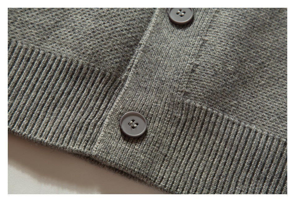 Close-up of two buttons, ribbed hem, and textured gray cardigan knit.