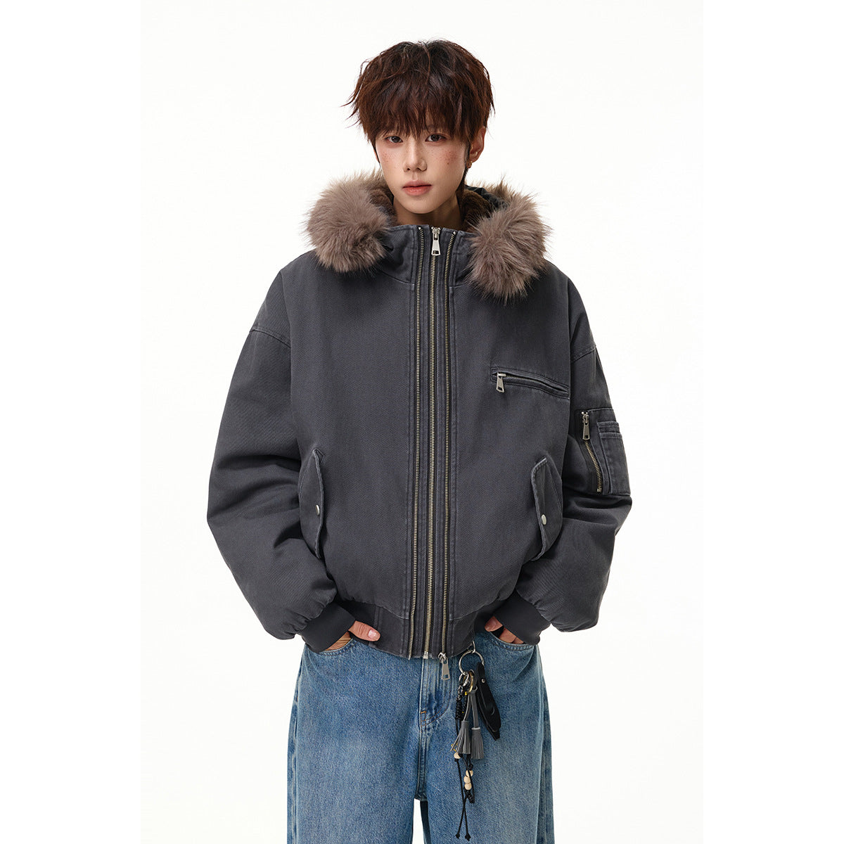 Model wearing a charcoal hooded bomber jacket with taupe fur trim, multiple zip pockets and a double front zipper.