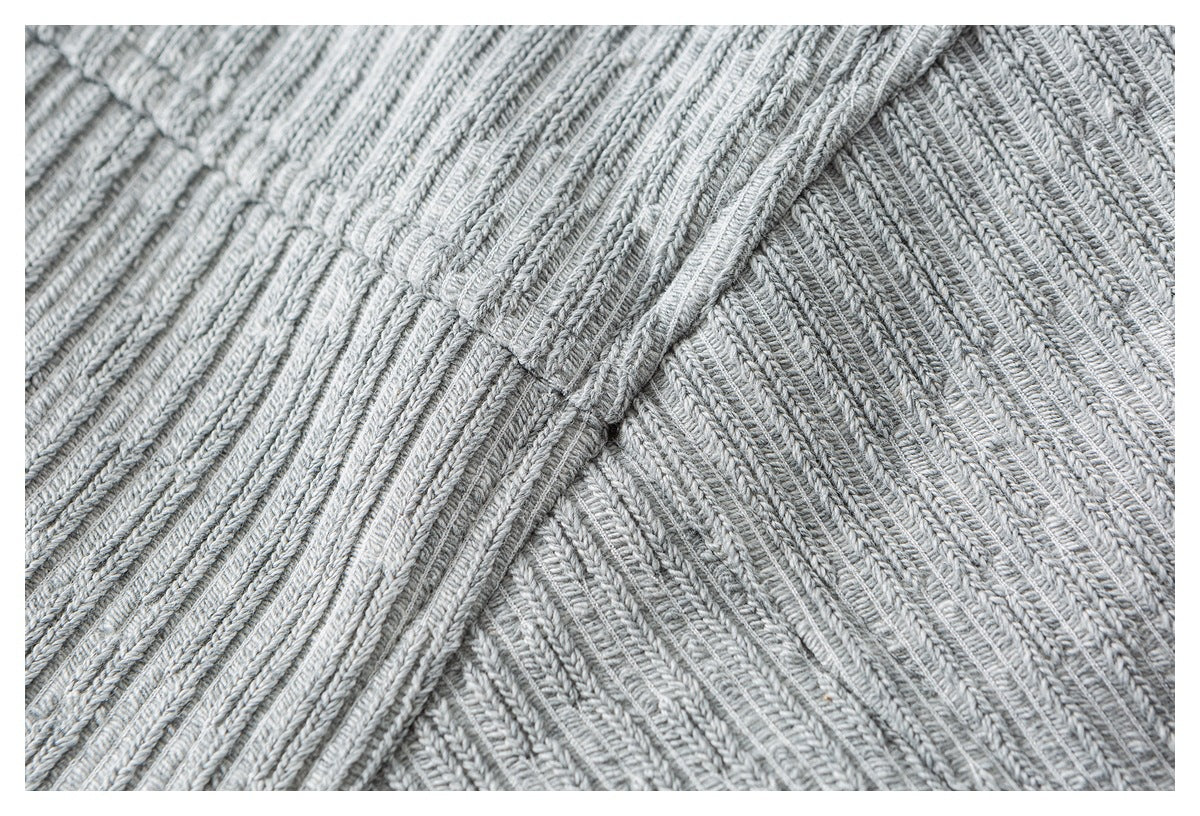 Close-up of intersecting seams and rib-knit texture on the light gray sweater.