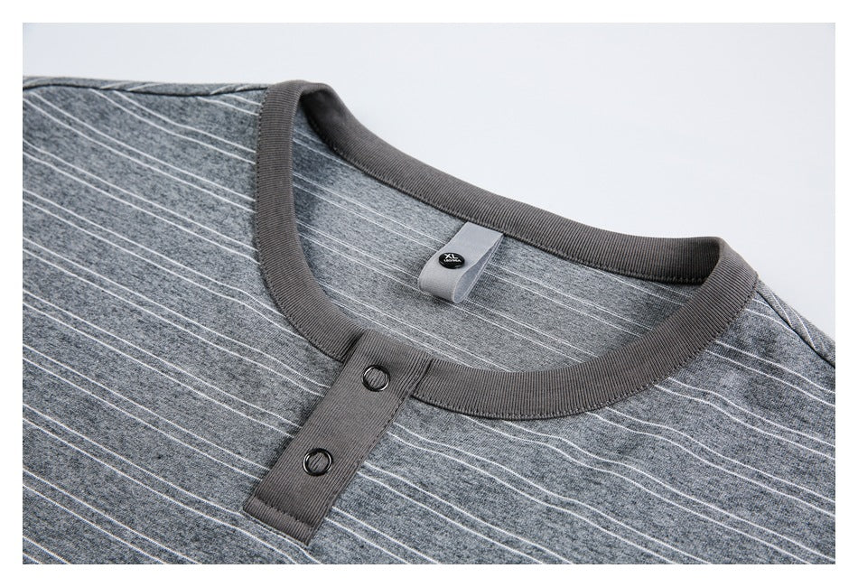 Close-up of a gray striped knit top's ribbed crew neckline and two-button placket.