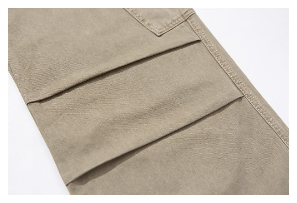 Close-up of beige trousers showing layered pleats and a stitched side seam.