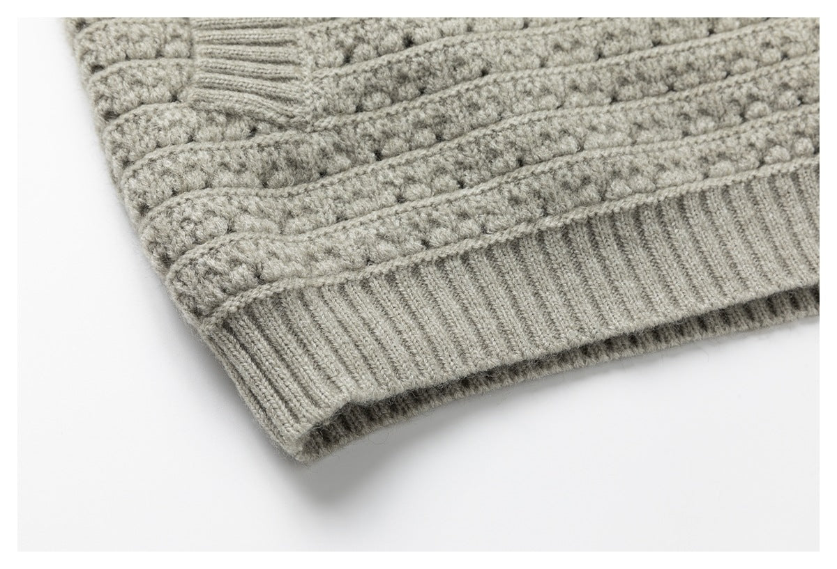 Close-up of a light gray textured knit sweater hem with a wide ribbed edge.