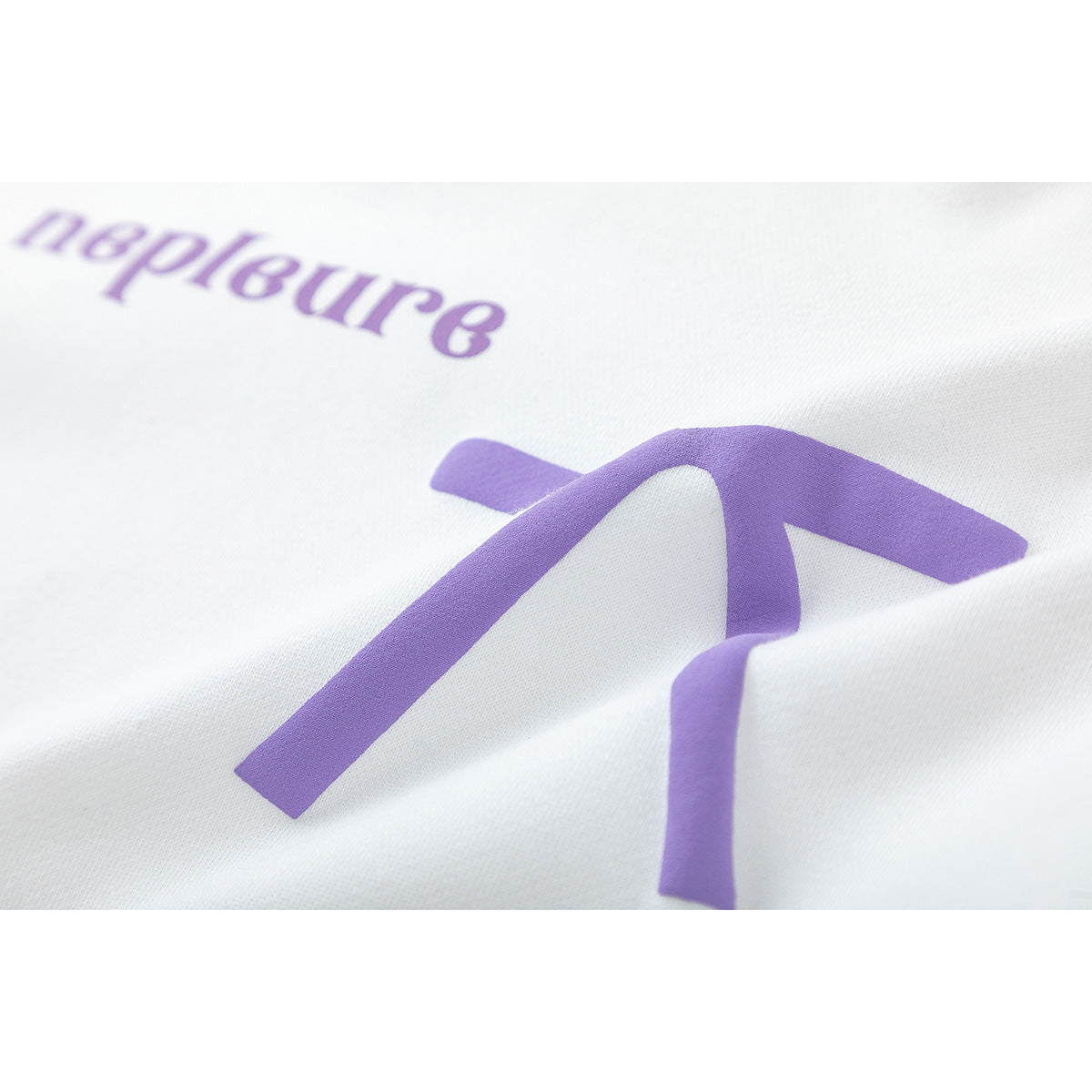 Close-up of purple lettering and a bow-like graphic printed on white hoodie fabric.