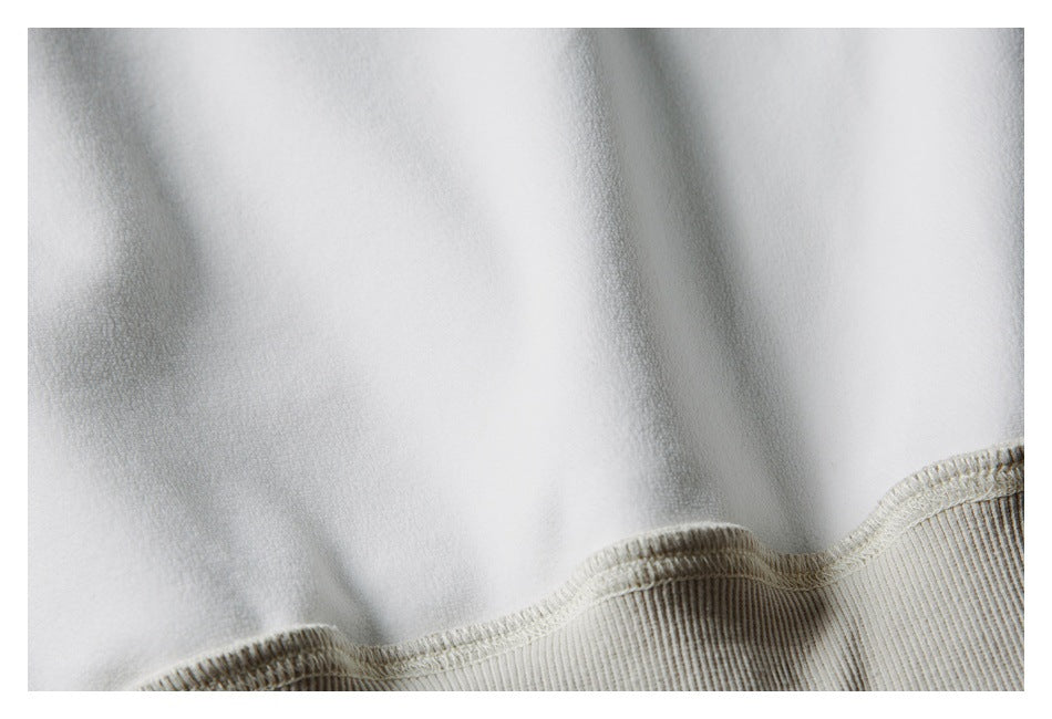 Close-up of an ivory garment's ribbed edge and visible stitching on the reverse side.