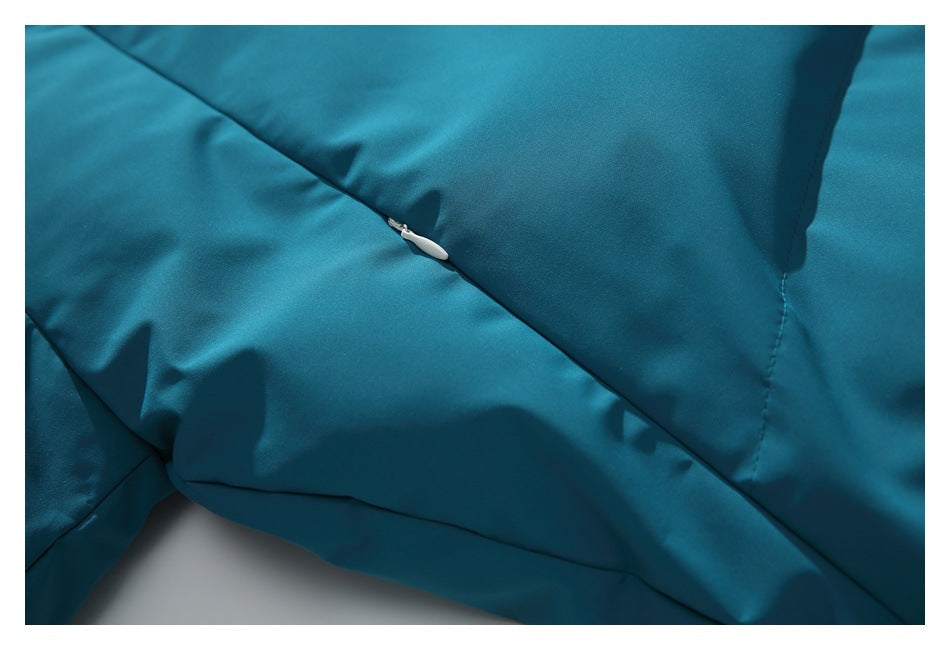 Close-up of a small white zipper set into the teal jacket fabric.