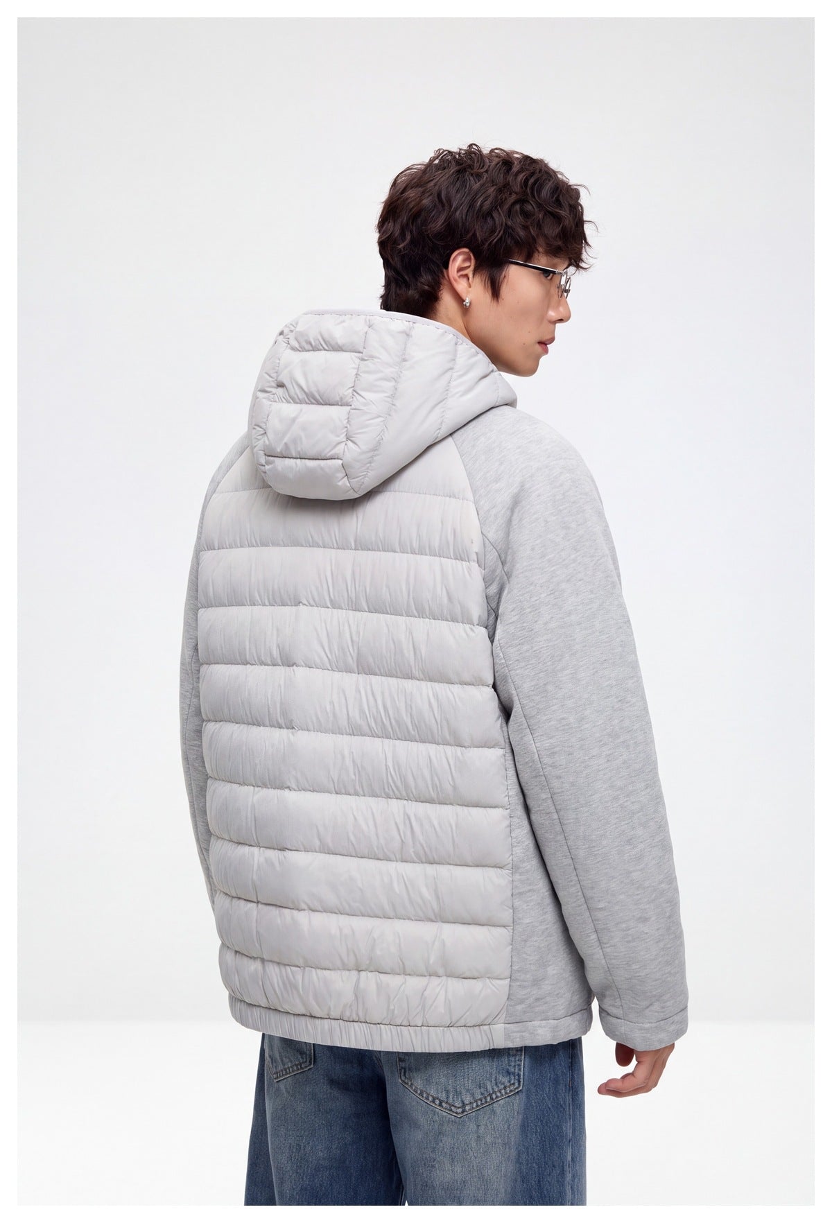 Back view of a model wearing the light gray quilted hooded jacket with heather gray sleeves.