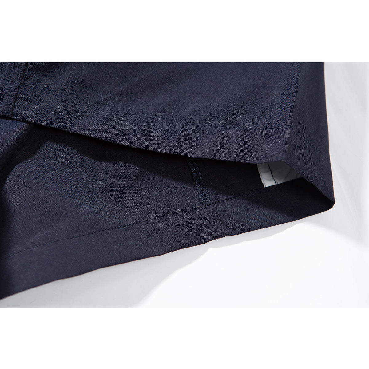 Close-up of the stitched hem and inner seam of navy shorts.