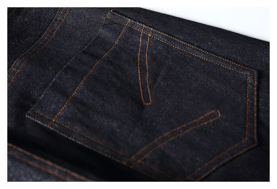 Close-up of a dark denim back pocket with orange contrast stitching.