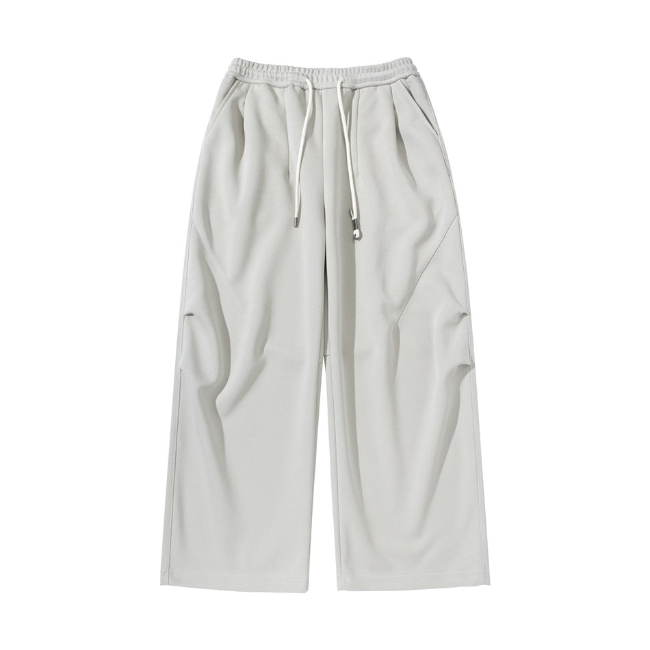 Light beige wide-leg drawstring pants with elastic waist, front pleats and diagonal thigh seams, flat front view