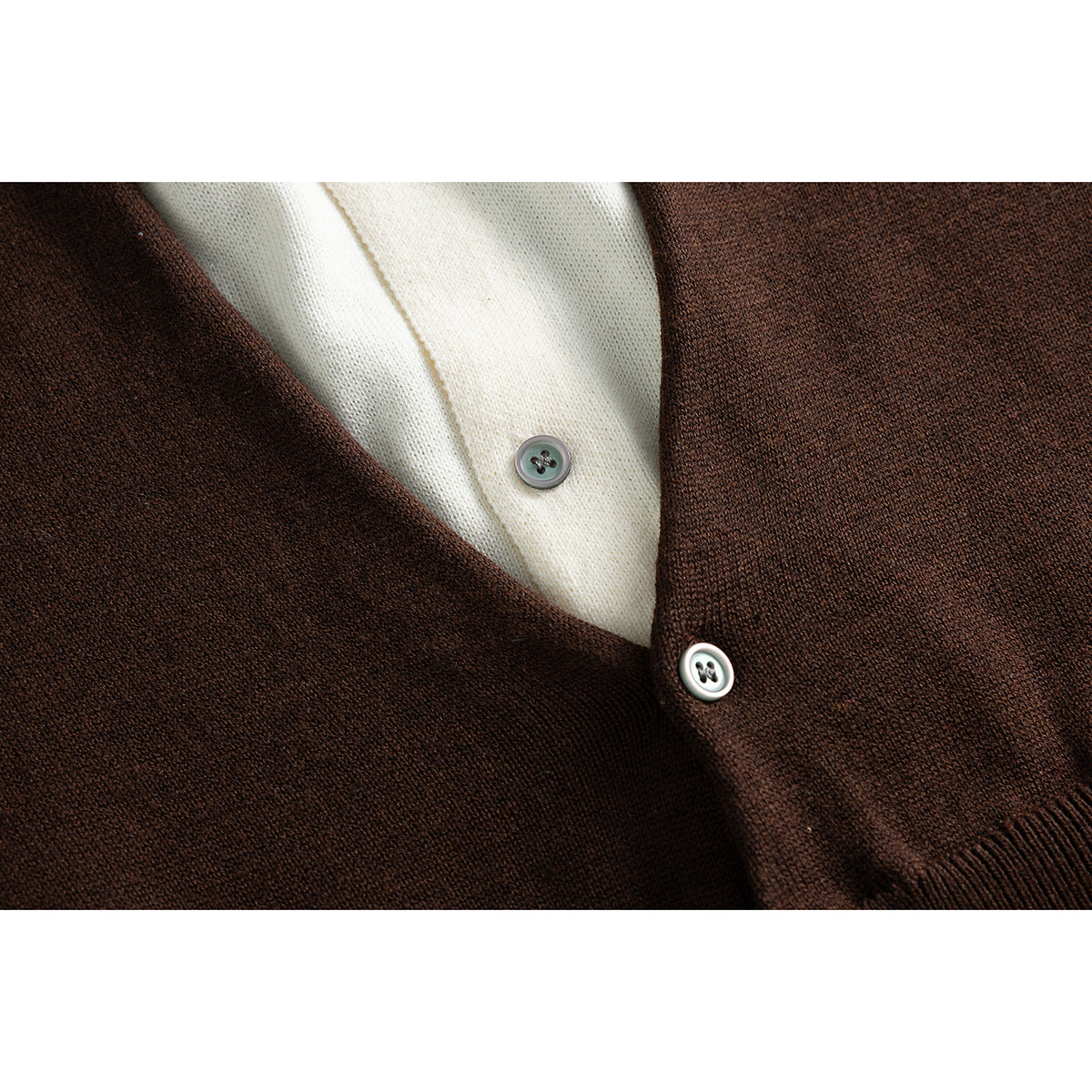 Close-up of a dark brown cardigan's button front over an ivory high-neck garment.