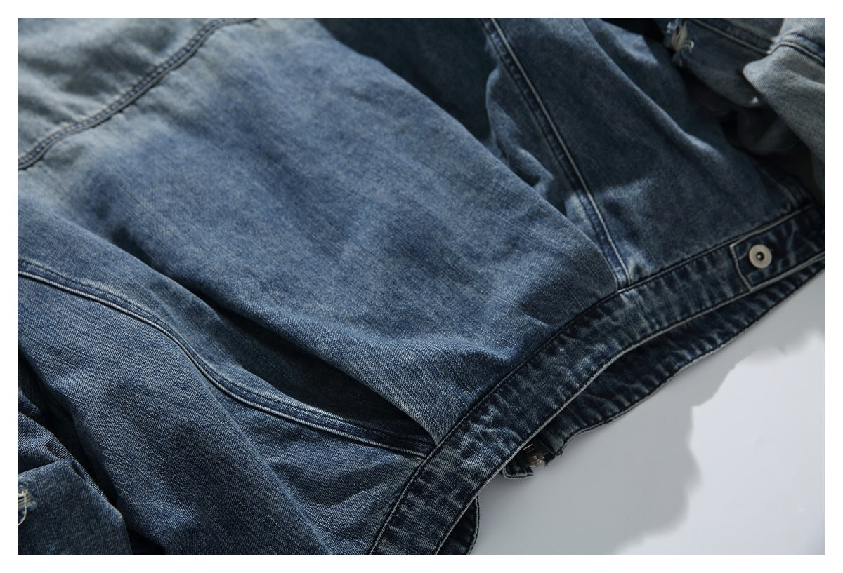 Close-up of the blue denim jacket's lower back panel, hem, and buttoned side tab.