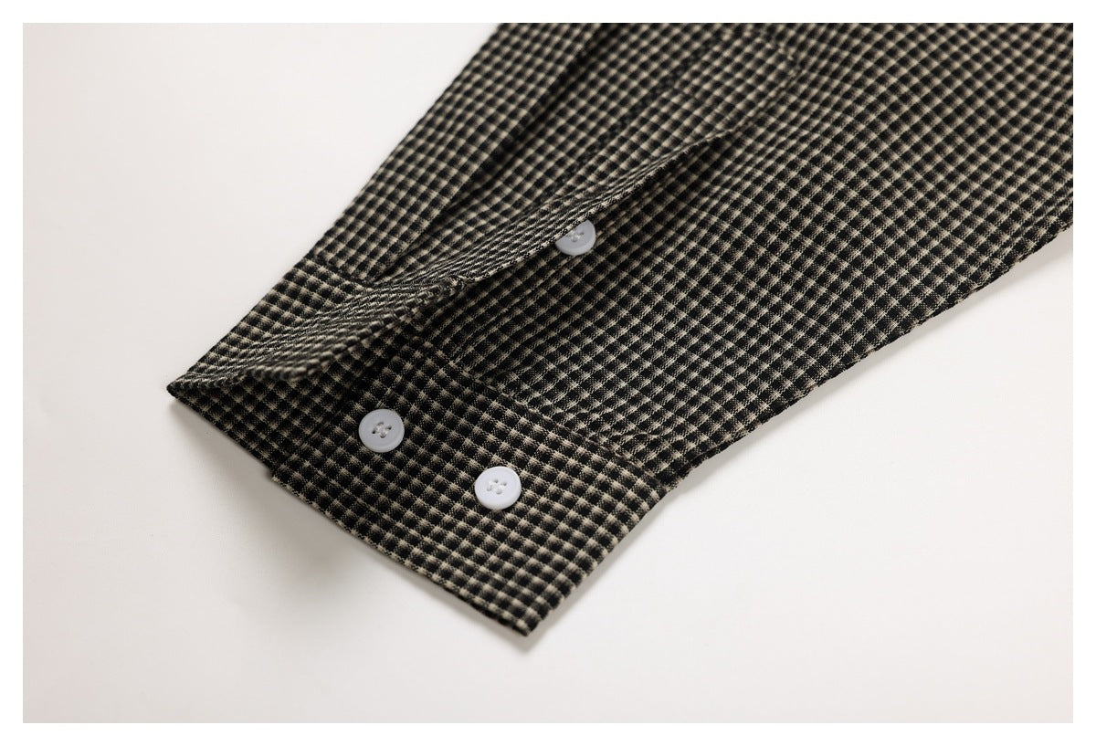 Close-up of black-and-beige checked fabric with a folded edge and three white buttons.