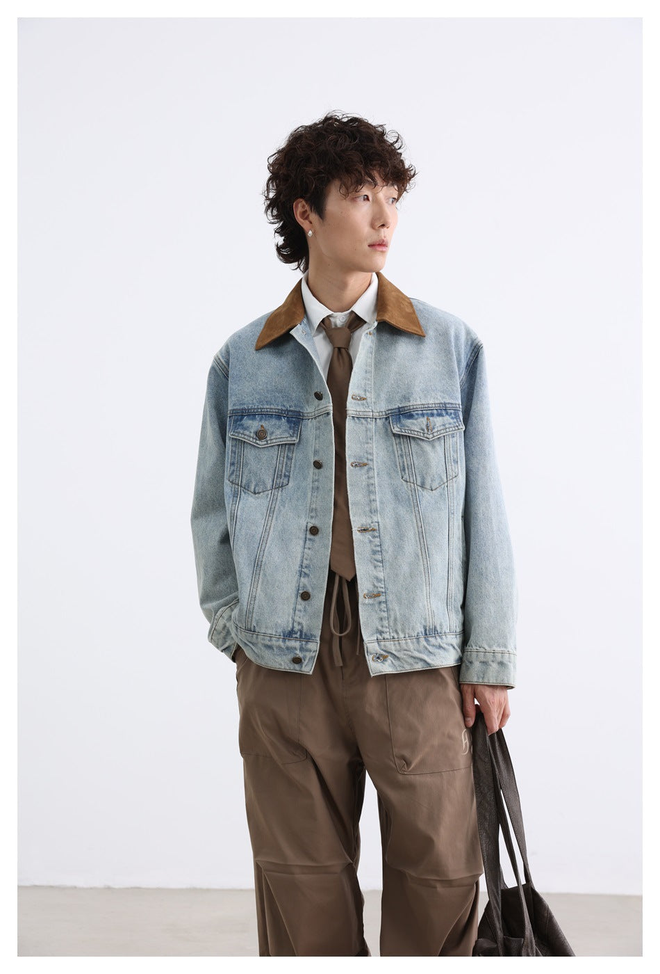 Model shown from the front wearing a light-wash denim jacket with a brown collar and loose brown trousers.