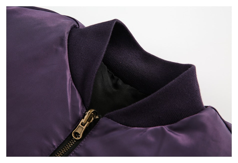 Close-up of a dark purple jacket's ribbed collar and brass-tone front zipper.