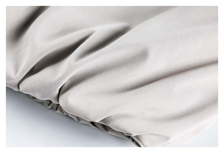 Close-up of softly gathered pale gray-beige fabric along an elasticized edge.