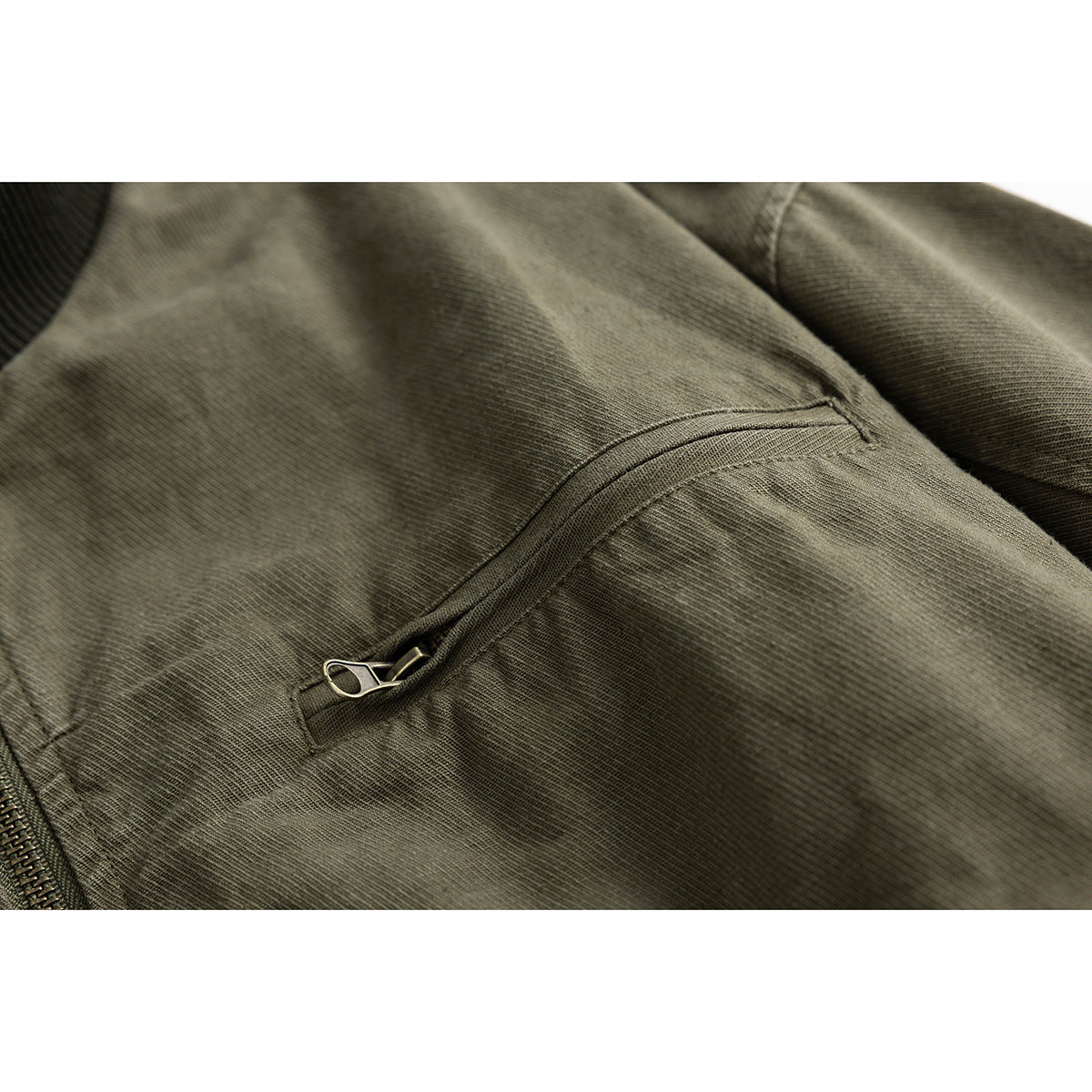 Close-up of an olive jacket’s diagonal zippered chest pocket.