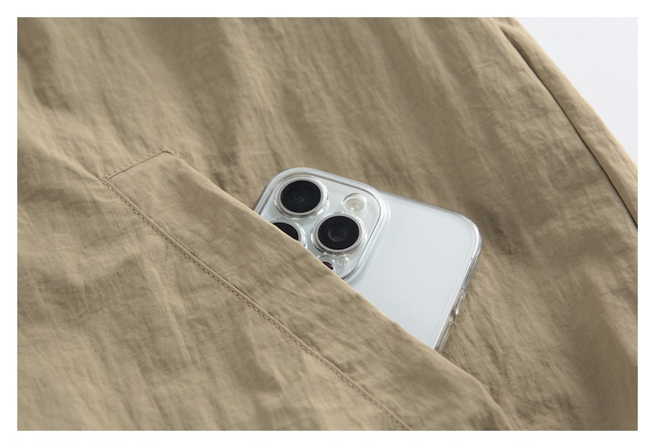 Close-up of a slanted pocket on tan jacket fabric, with a smartphone tucked inside.