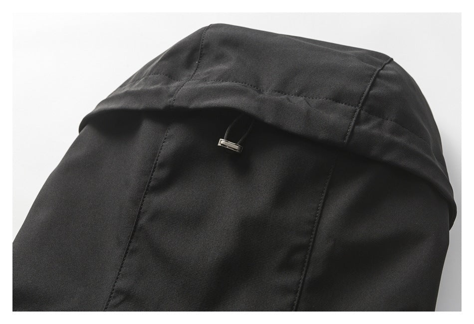 Close-up of a black jacket hood with stitched panels and a small adjustment tab.