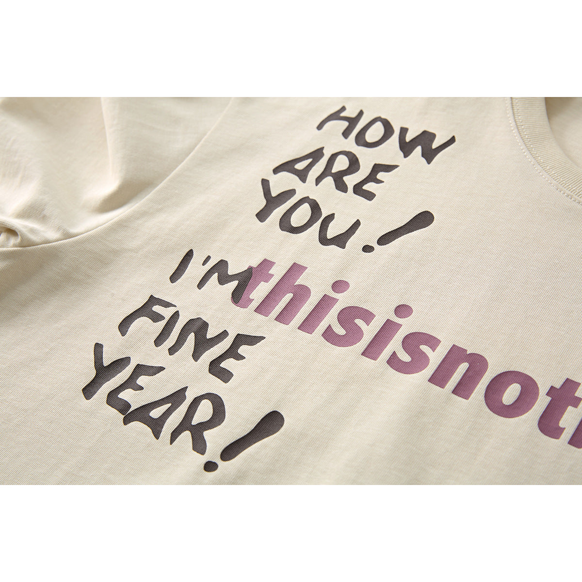Close-up of a cream T-shirt printed with the phrases “HOW ARE YOU!” and “I'm thisisnotbrand” in dark and mauve lettering.