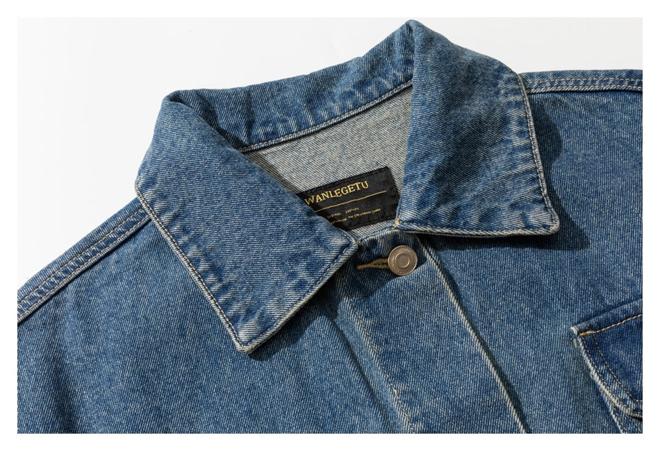 Close-up of the blue denim jacket's pointed collar, top button, stitching, and sewn-in neck label.