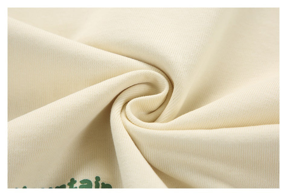 Ivory fabric gathered into a swirl, with part of a green print visible at the lower edge.