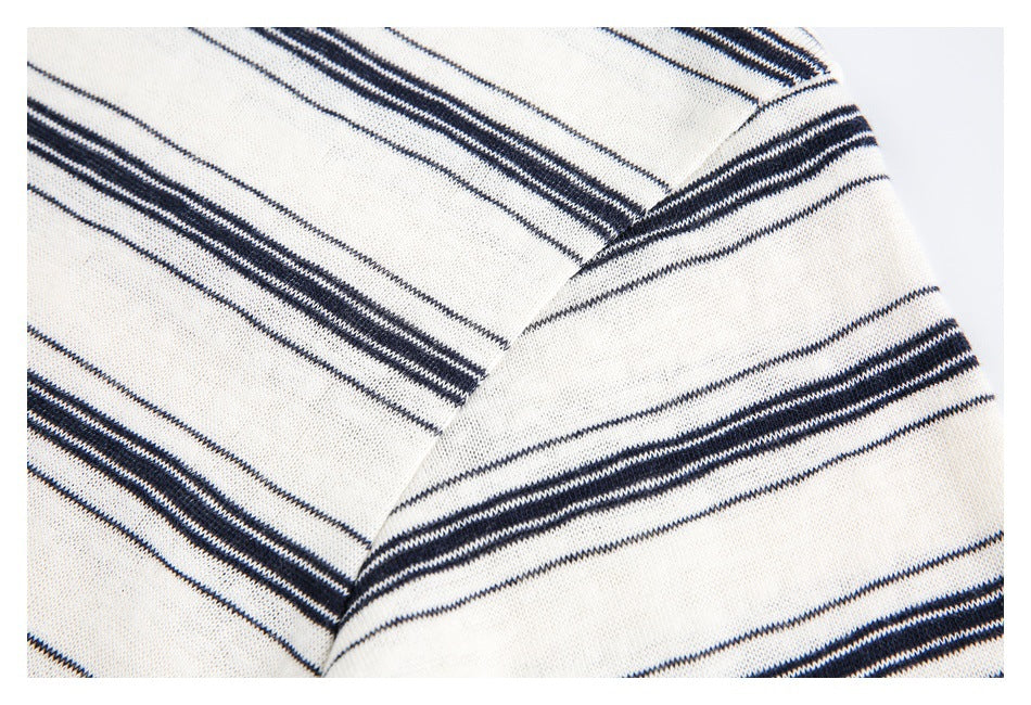 Close-up of a shoulder seam joining ivory fabric with narrow navy stripes.